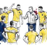Soccer coach speaking to a group of players in yellow jerseys, forming a circle on the field